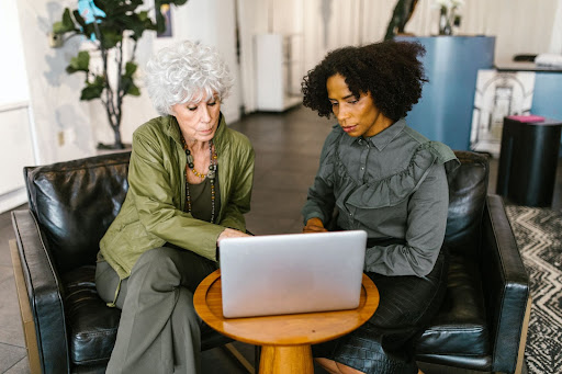 Two women sitting in front of a laptop in an office space
