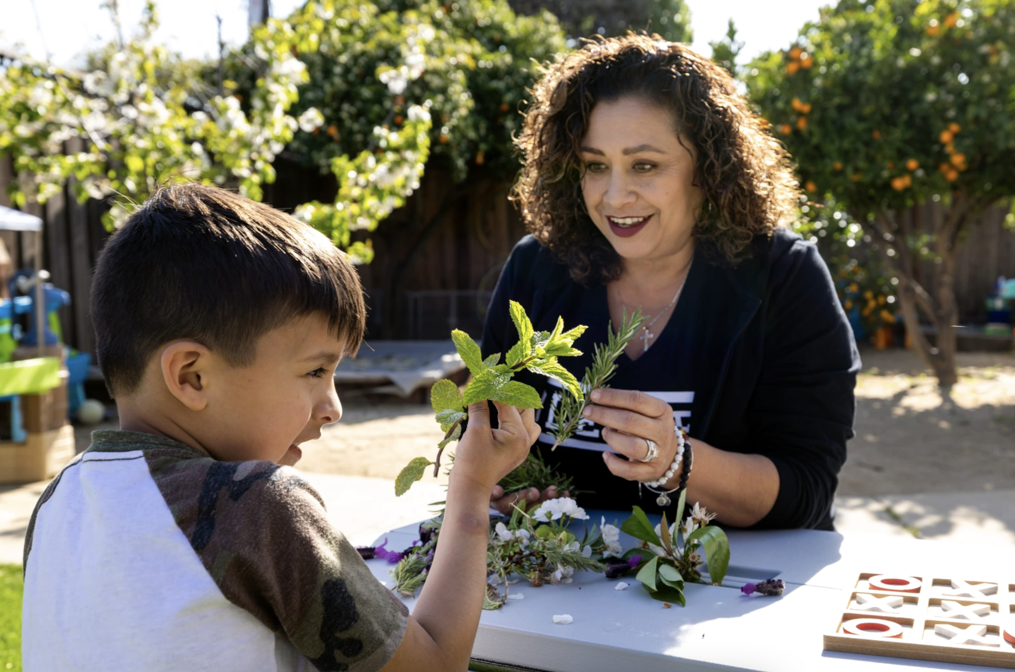 Woman helps boy make bouquet for his mother.